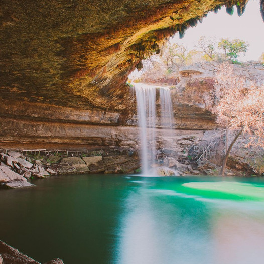 Waterfall falling into a turquoise pool beneath a rocky overhang