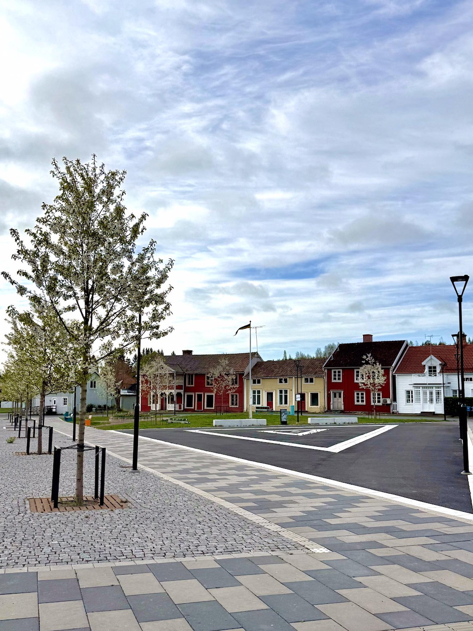 Town square with colorful houses and trees under cloudy sky