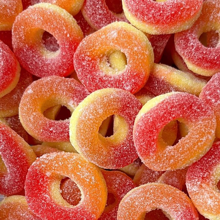 Pile of sugar-coated peach ring gummy candies in red, orange and yellow colors