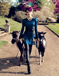 Woman in teal dress walking two dogs on a garden path