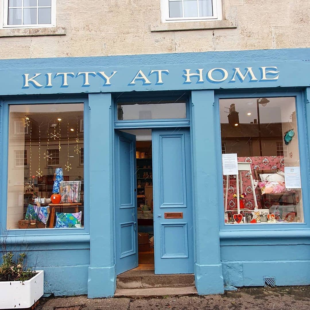 Blue storefront exterior with open door and decorated display windows