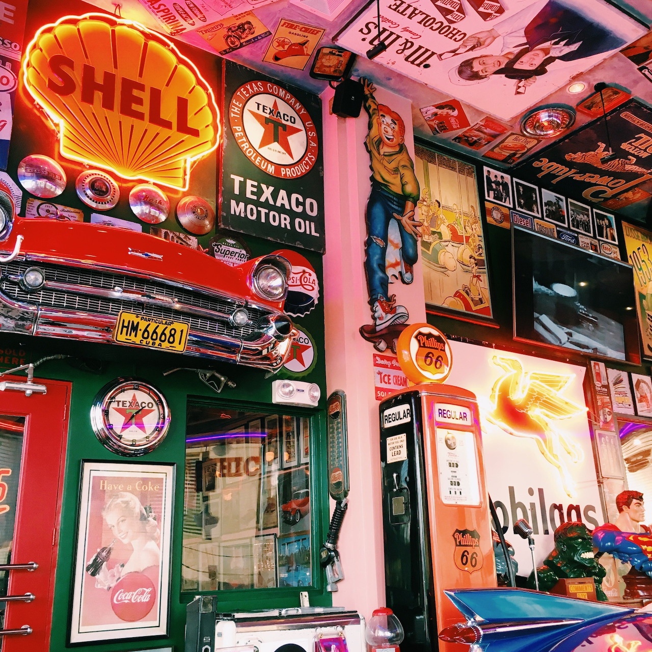 Retro interior with vintage gas station signs, classic car front, and old fuel pumps