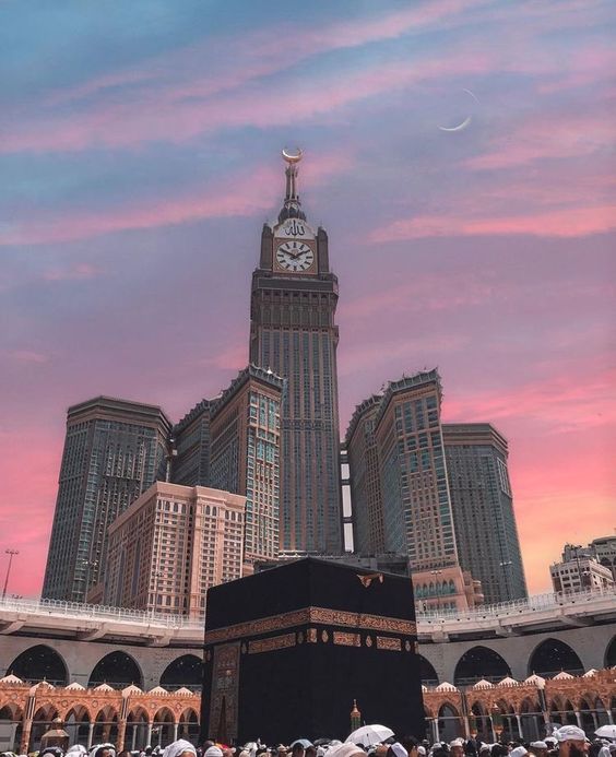 The Kaaba with the Makkah clock tower behind it at sunset