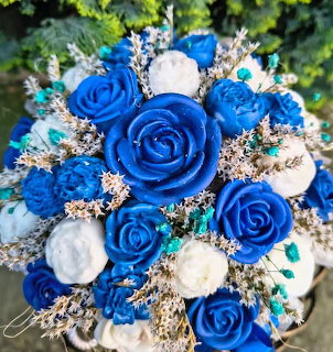 Close-up of a bouquet with blue and white roses, filler sprigs, and green leaves