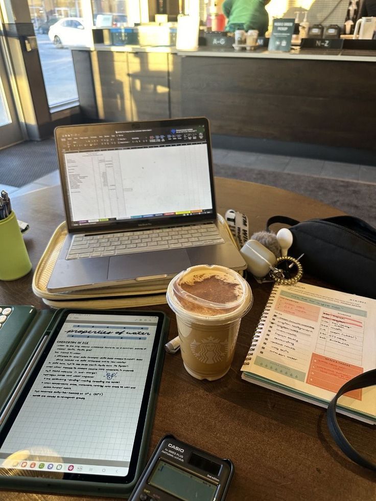 Person working on laptop with coffee cup at a wooden cafe table