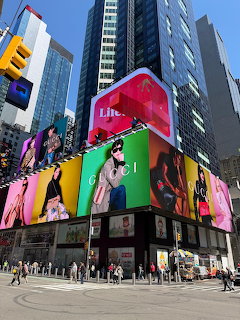 Large wraparound LED billboard on Times Square building corner showing bright pink and multicolored advertisements