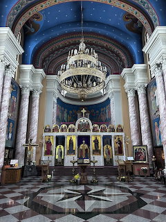 Interior of Orthodox church with chandelier, iconostasis, columns and decorated blue dome
