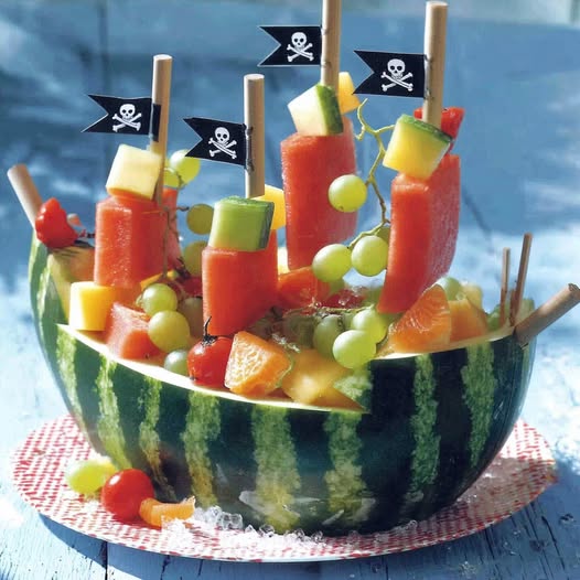 Watermelon carved as pirate ship with fruit skewers and pirate flags