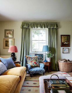 Traditional living room with gold sofa, patterned chair, green curtains, and framed artwork on textured walls