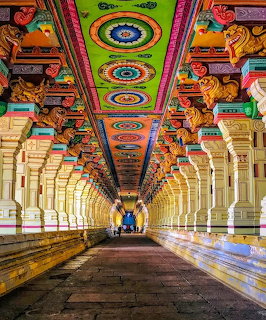 Ornate multicolored gopuram tower of Meenakshi Temple in Madurai with detailed Hindu deity sculptures.