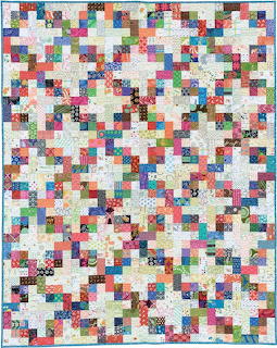 Colorful patchwork quilt with small fabric squares in rainbow colors separated by white sashing