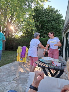 People chating on a stone patio in a backyard garden at sunset with trees in the background