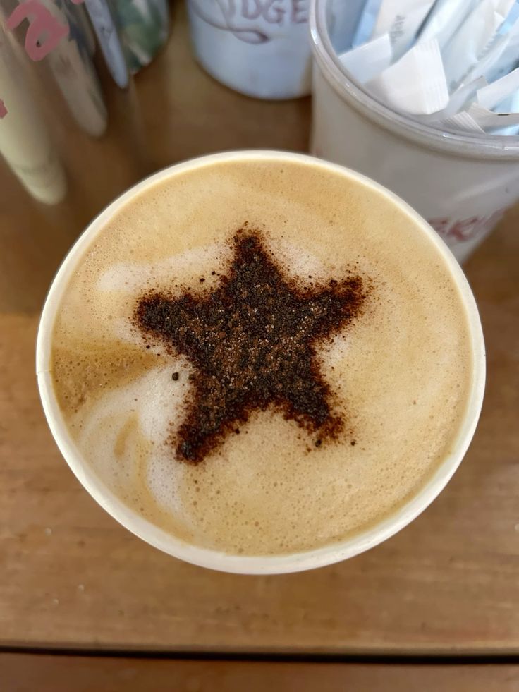 Cappuccino with star-shaped latte art design in brown cocoa powder on light foam, viewed from above