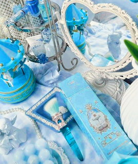 Blue coquette aesthetic flat lay with perfume, carousel, heart mirror, and vintage accessories