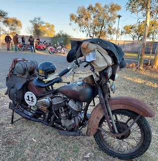 Vintage Harley-Davidson WL motorcycle with aged paint and number 11, parked on dirt with trees behind