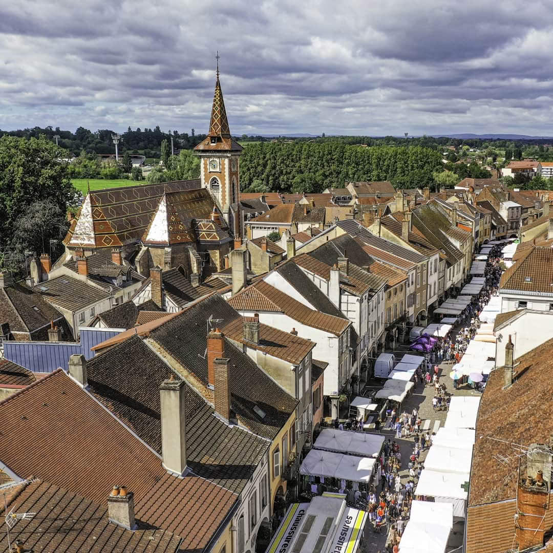 Aerial view of historic French village with church and rooftops under cloudy sky