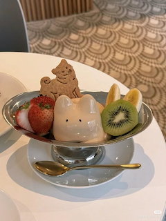Ice cream dessert with cat face, chocolate swirl, strawberries, kiwi and banana in glass bowl