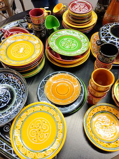 Colorful hand-painted ceramic plates and cups stacked on a table at an antiques market