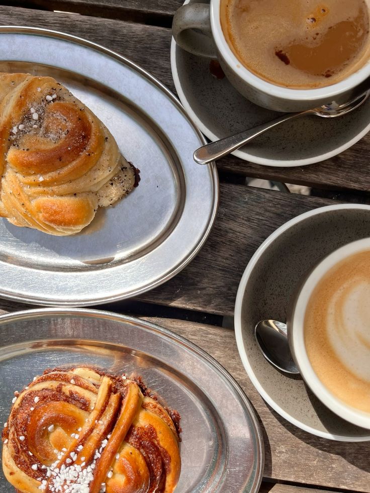 Top-down view of coffee cups and cinnamon rolls on wooden table