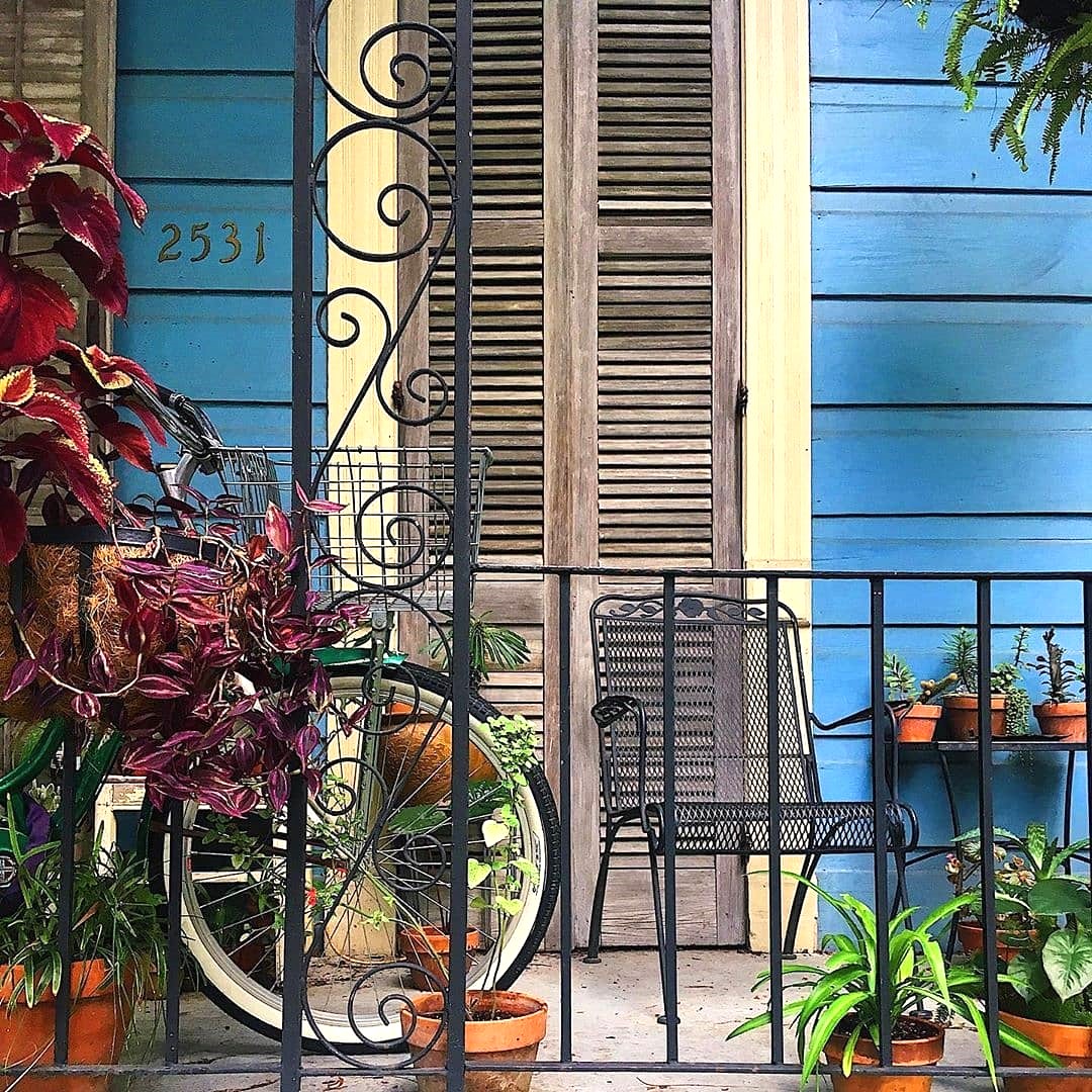 Vintage bicycle leaning on blue wooden porch with plants and decorative ironwork