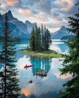 Spirit Island on Maligne Lake surrounded by turquoise water, evergreen trees, and rocky mountains at dusk