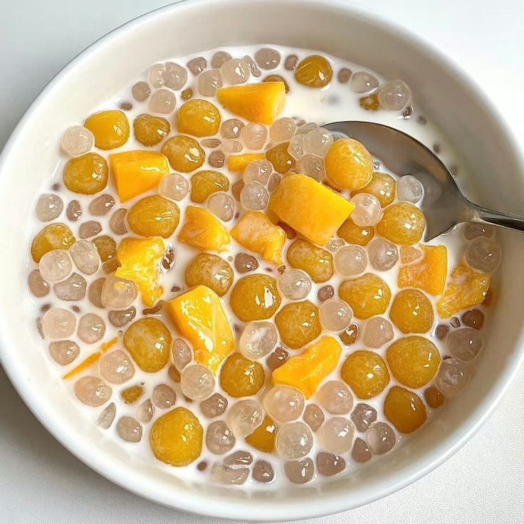 Overhead view of mango sago dessert bowl with boba pearls and fresh mango chunks in coconut milk