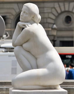 White marble sculpture of seated female figure in Barcelona plaza
