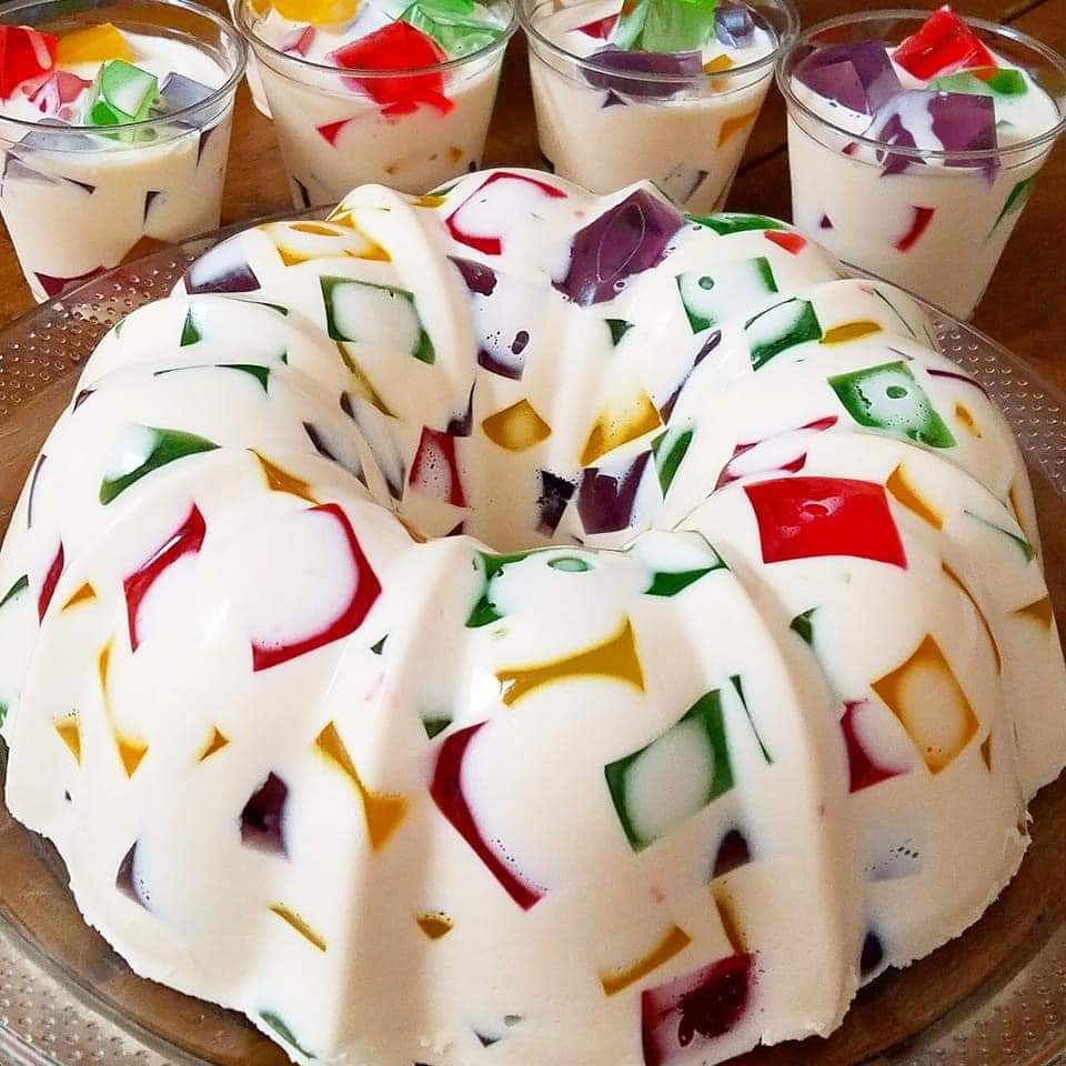 White mosaic gelatin bundt cake with colorful jelly cubes and dessert cups in background