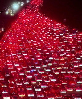 Dense traffic jam with rows of cars showing red brake lights on highway at night
