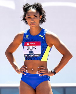 Female athlete in blue racing uniform and competition bib standing with hands on hips