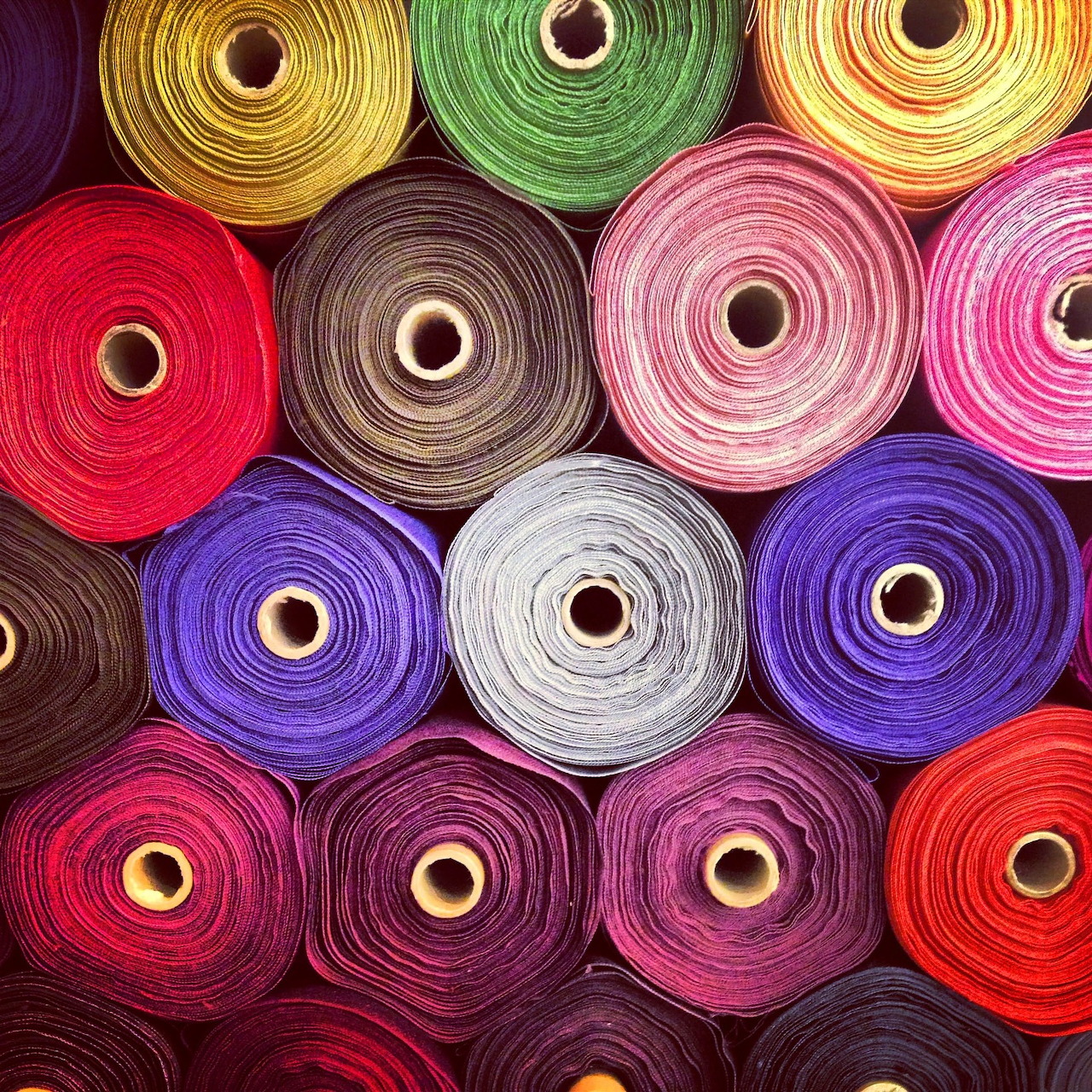 Colorful fabric rolls or thread spools arranged in rows showing rainbow spectrum of colors