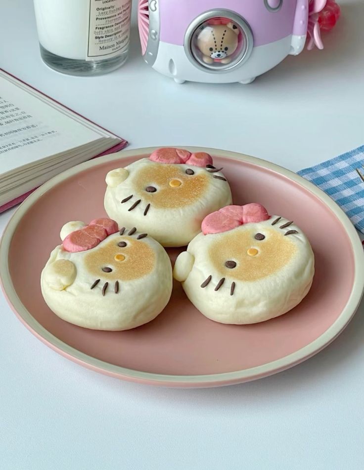 Three Hello Kitty-shaped bread buns with pink bows on a pink plate