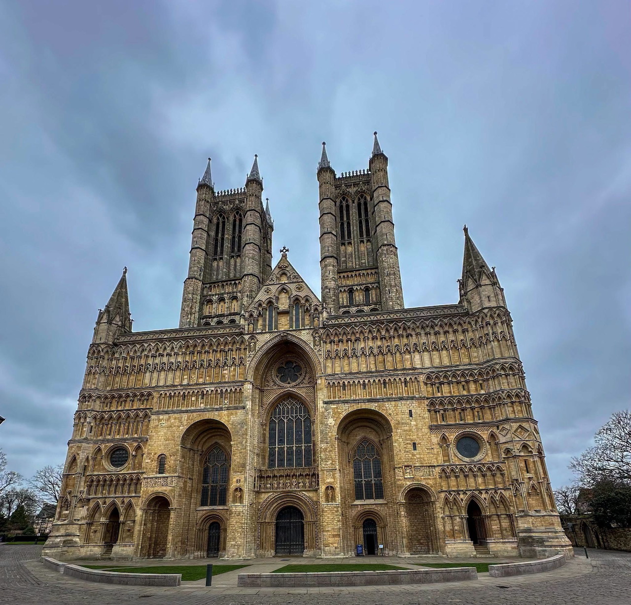 Gothic cathedral with twin towers and ornate medieval stone facade against cloudy blue sky