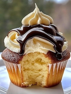 Boston cream pie cupcake with chocolate ganache dripping over cream frosting, showing vanilla cake interior