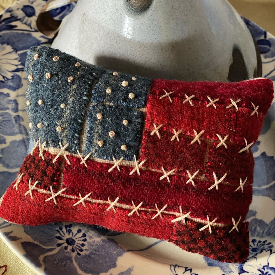 Small stitched patchwork pillow with an American flag design on blue floral fabric