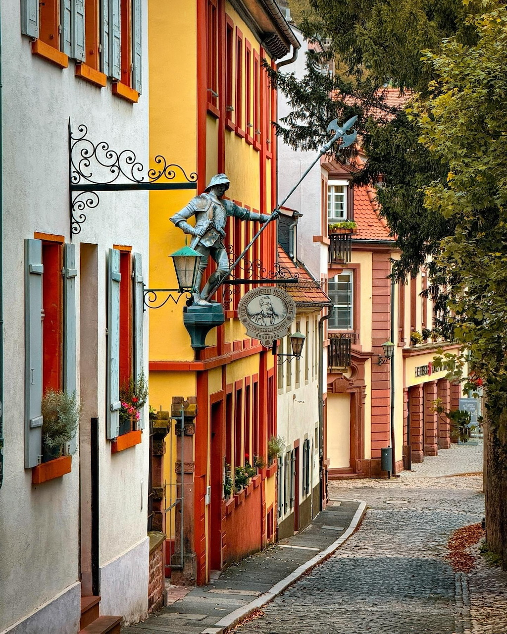 Narrow cobblestone street lined with colorful traditional buildings and ornate street lamp in Heidelberg, Germany