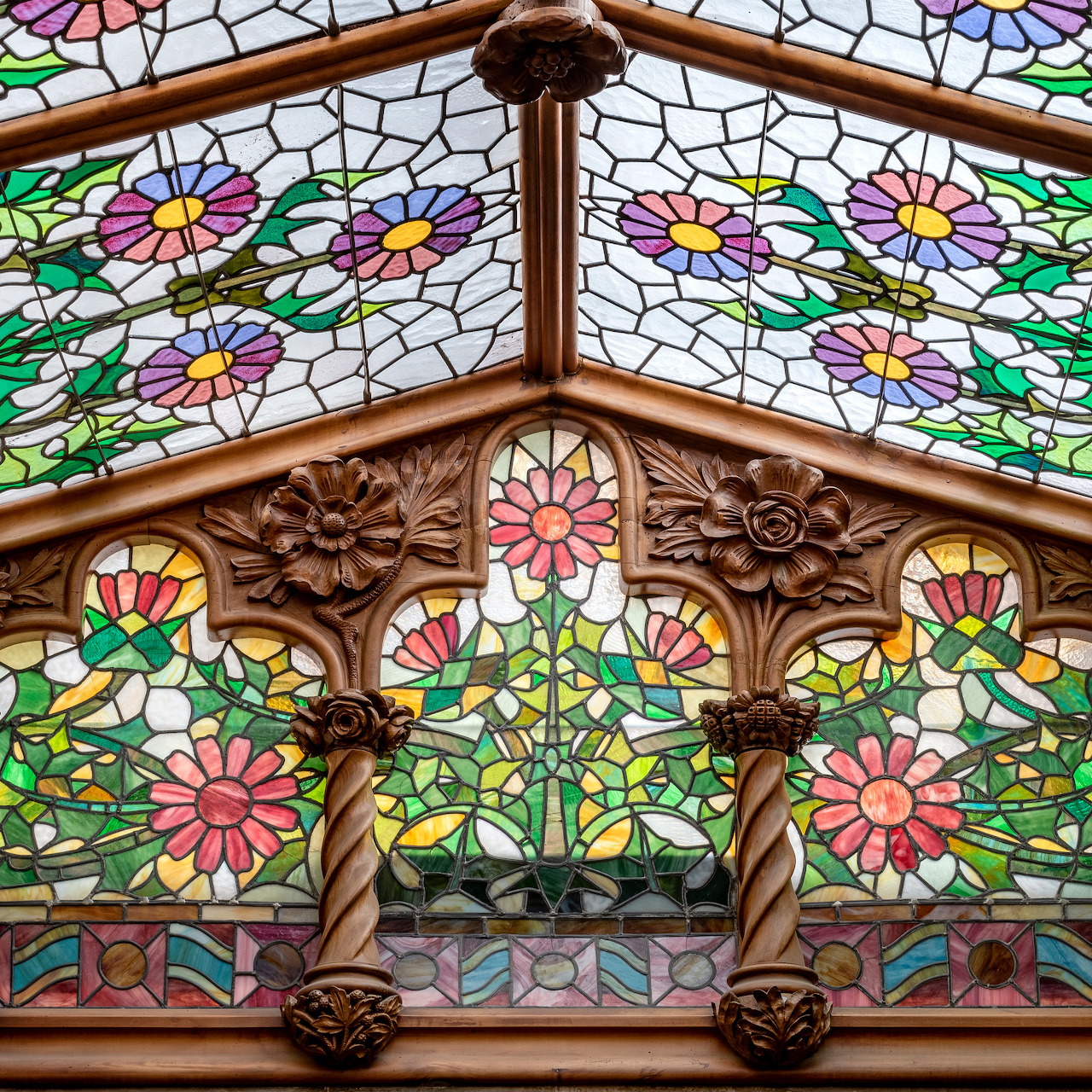 Ornate wooden building facade with stained glass floral panels and carved decorative frame