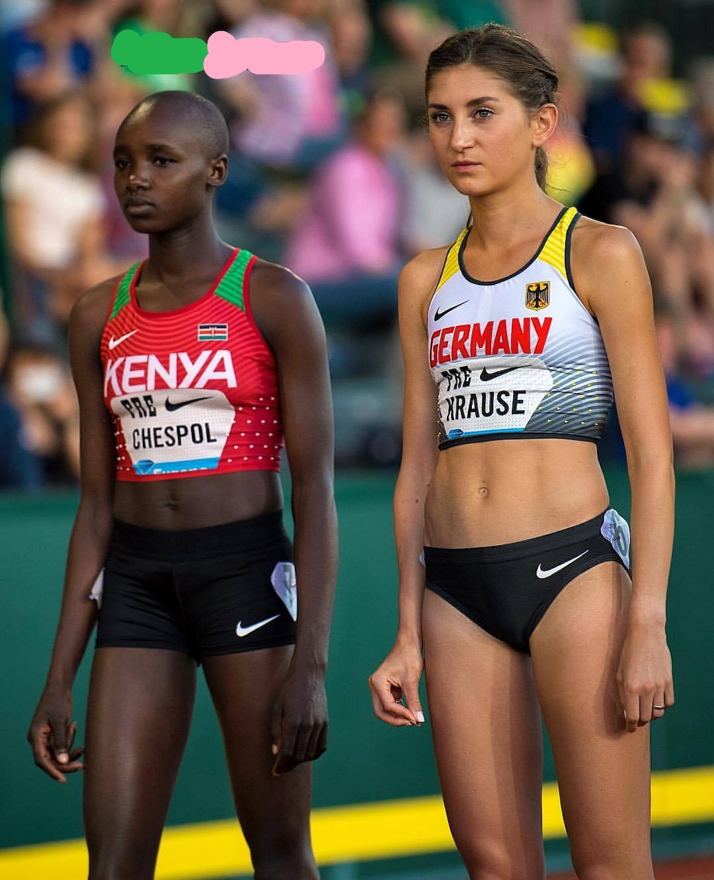 Two female track athletes in national team uniforms standing side by side on a track