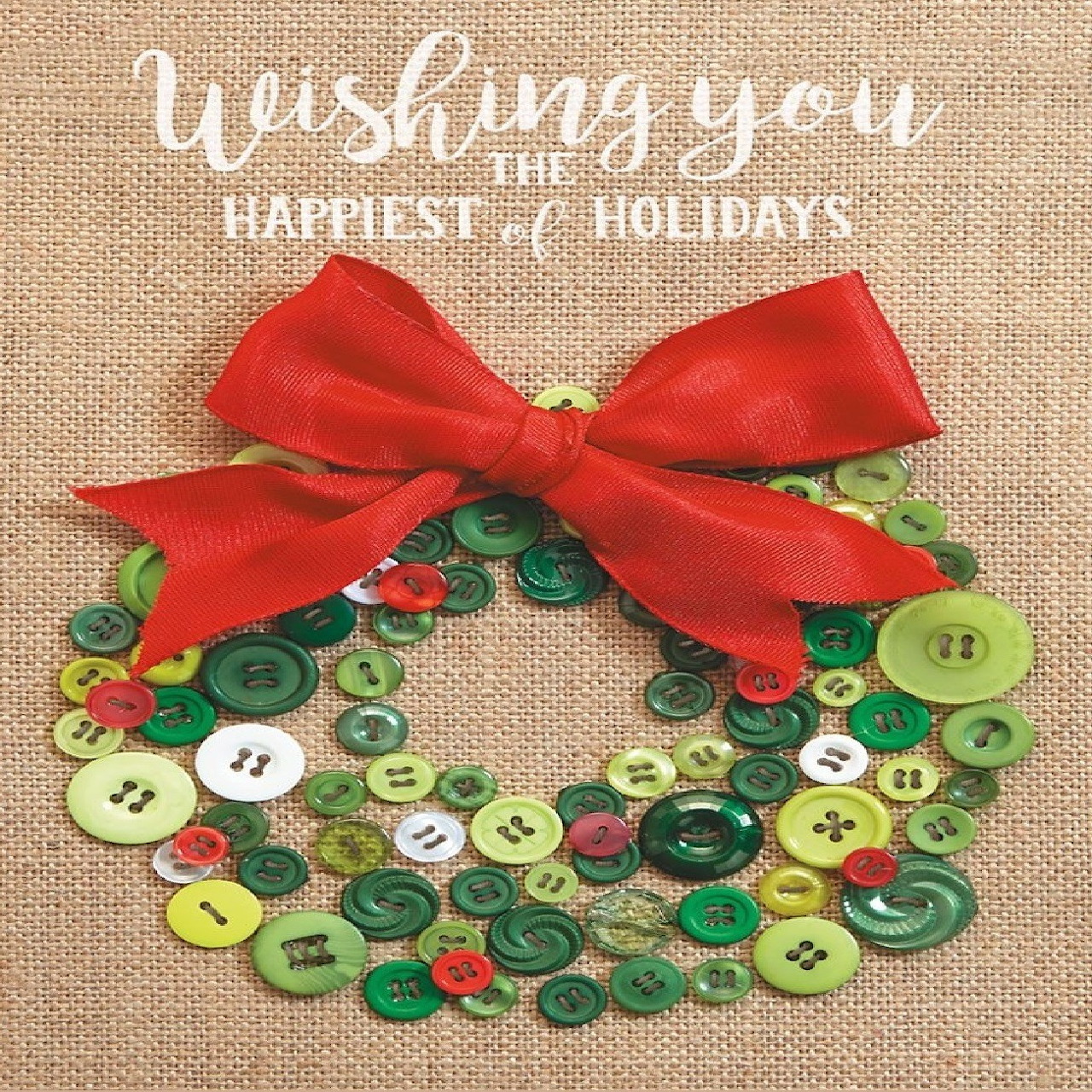 Green button wreath with a red bow on burlap and holiday greeting text above