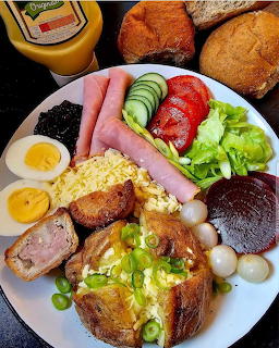 British platter with ham, cheese, eggs, vegetables, bread and condiments on white plate