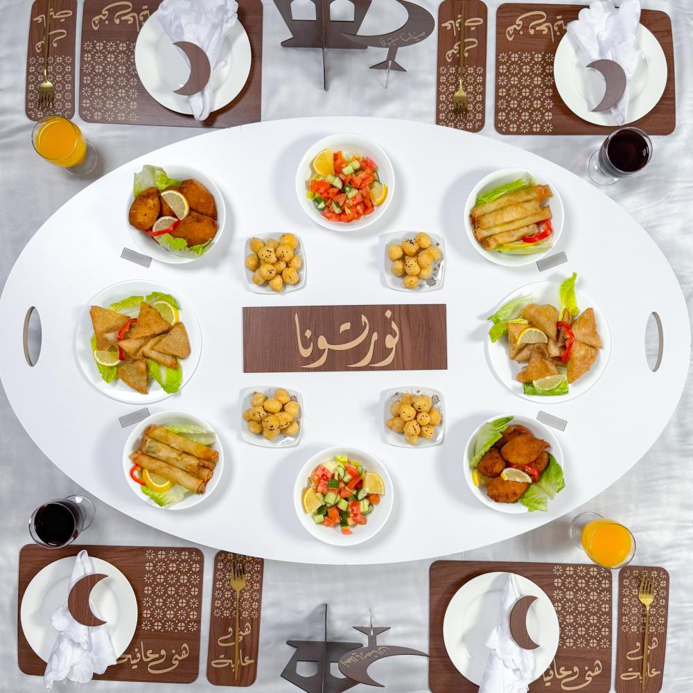 Overhead view of oval dining table with plates of food, placemats, and tea service arranged symmetrically