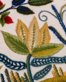 Detailed embroidery showing stylized leaves and flowers with colorful thread on white fabric