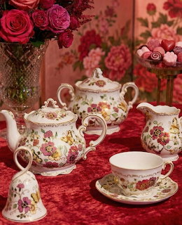 Ornate floral porcelain coffee set with roses on red velvet tablecloth
