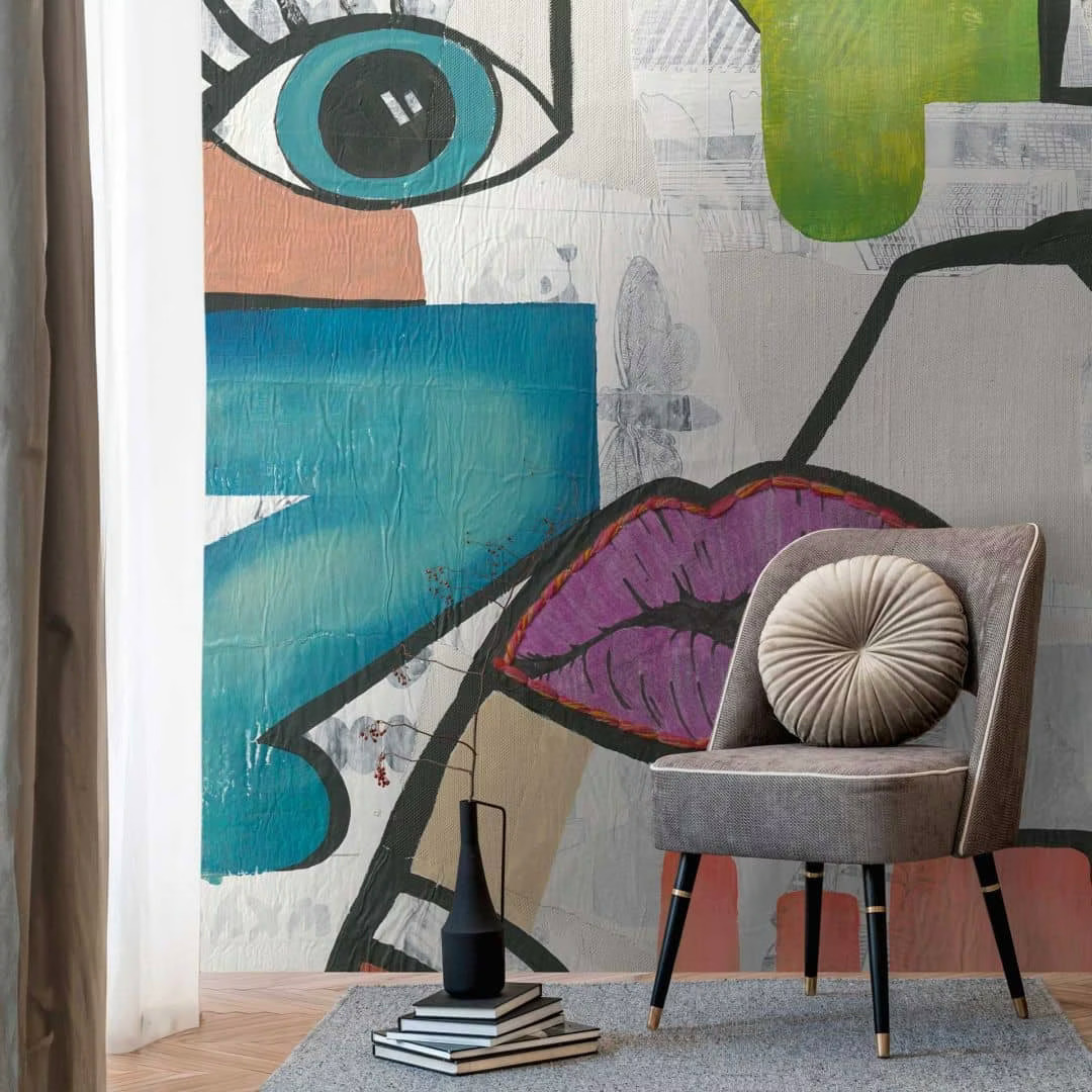 Modern room corner with abstract wall art, gray chair, books, and black vase