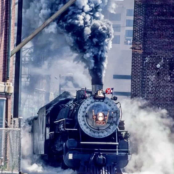 Black steam locomotive 441 emitting large plumes of white steam on railroad tracks viewed from above