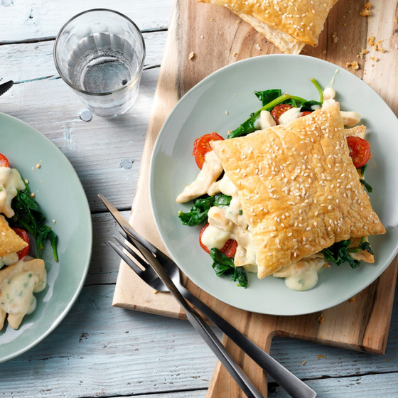 Puff pastry dish with chicken and spinach filling on a mint plate with cutlery and glass of water