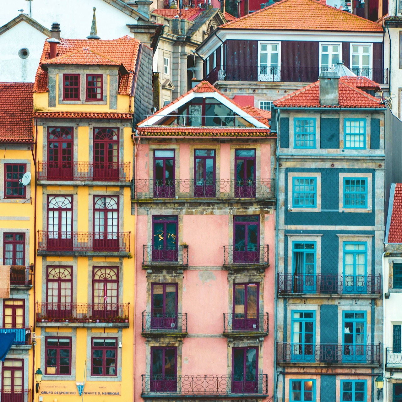 Colorful traditional Porto buildings with terracotta roofs in yellow, pink and teal