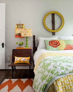 Bedroom with colorful quilt bedding, pillows, bedside table, and wheel wall decoration