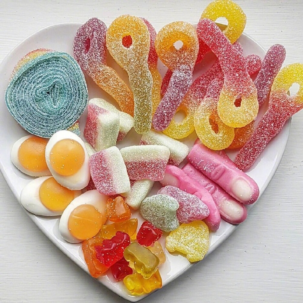 Heart-shaped dish filled with assorted colorful gummy candies and marshmallows