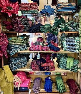 Shop shelves displaying colorful folded scarves, gloves, and woven textiles in various patterns and colors